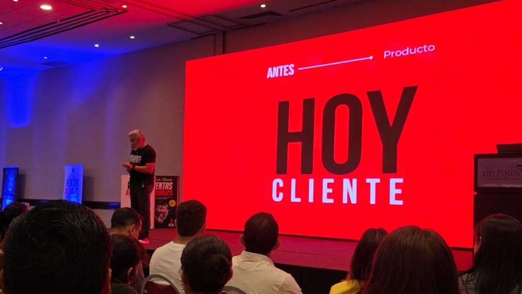 Sandro Meléndez en el escenario del seminario Ventas Salvajes, con la frase 'Antes Producto, Hoy Cliente' proyectada en pantalla roja.
