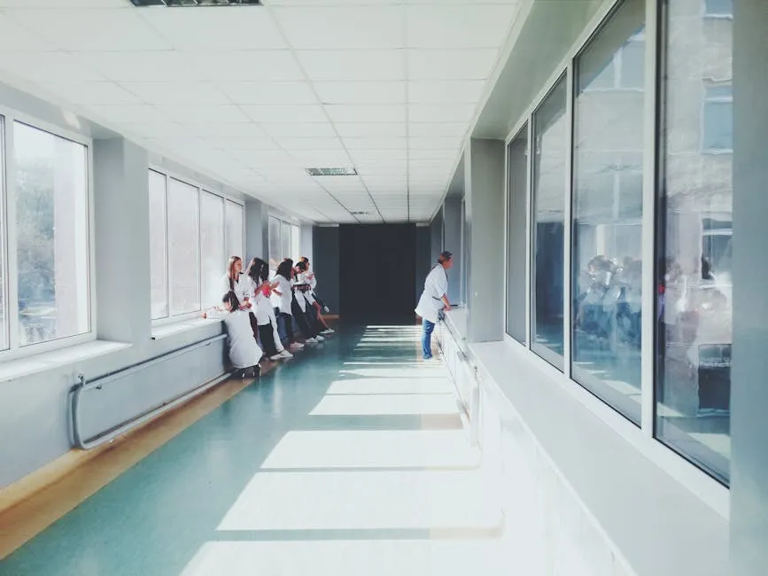 Pasillo de hospital iluminado con personal médico en batas blancas.
