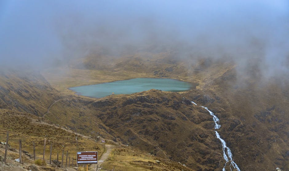 A serene view of Lake Huaytapallana with misty mountains in Junín, Peru.