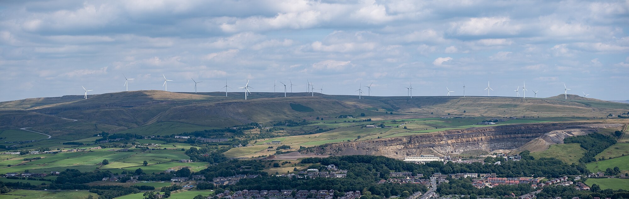 Panorámica del parque eólico Scout Moor visto desde el Peel Monument — paisaje donde la transición energética (NIIF S2) y el valor del suelo (NIC 16) deben medirse y revelarse.